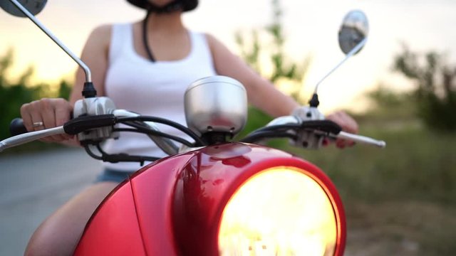 Woman on moped. Headlight lamp of red vintage motorcycle or scooter. Dolly shot.