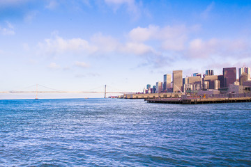 Obraz premium City of San Francisco California seen from the Bay with Bay Bridge, docks and buildings of skyline in view.