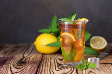 Glass of iced tea with mint and lemon. Cold drink. Rustic style