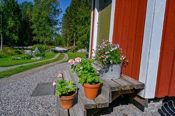 flowers on stairs infront of a red wooden cabin