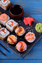 Sushi rolls assortment, wasabi, marinated ginger and soy sauce served on slate plate