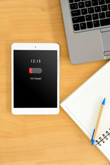 top view of business workspace to mobile phone with low charged battery screen, notebook and female hands typing on keyboard