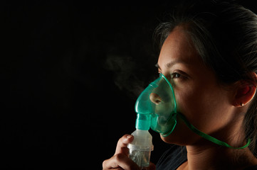 Close up view of woman using inhalation mask