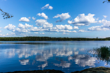 White clouds reflecting on the calm waters of the Saimaa lake in the Linnansaari National Park in...