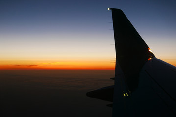 Looking out of airplane window at winglet and sunset
