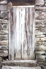 puerta de madera vieja y antigua pintada de blanco rodeada de muro de piedras en las Alpujarras en Andalucia, España