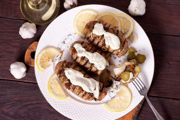 Baked potato with onions and spices on a white dish on the background of a wooden table