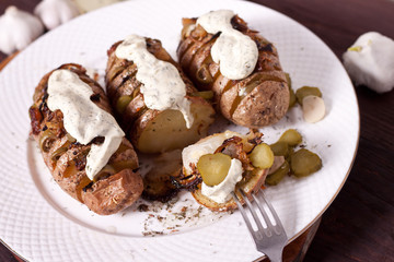 Fototapeta na wymiar Baked potato with onions and spices on a white dish on the background of a wooden table