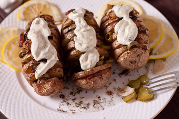 Baked potato with onions and spices on a white dish on the background of a wooden table