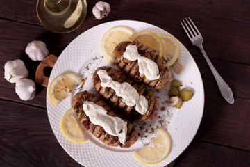 Baked potato with onions and spices on a white dish on the background of a wooden table