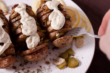 Baked potato with onions and spices on a white dish on the background of a wooden table