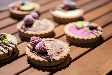 Raw vegan tartlets on the wooden table. Healthy desserts, close up