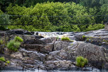 Fototapeta na wymiar Suspension bridge over a mountain river with a waterfall.
