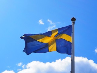 Fototapeta premium flag of sweden waving in the wind in front of blue sky