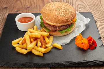 Burger with meat and potatoes on black slate
