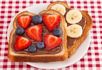 Pair of Fruit and Chocolate Hazelnet Spread Toast on a Red and White Plaid Tablecloth
