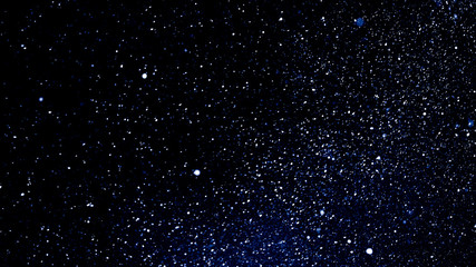 Winter night background - snowstorm against the black night sky, a lot of snowflakes