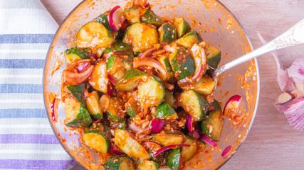 Oi Muchim Korean spicy cucumber salad in a glass bowl with a spoon.