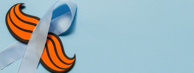 Flat composition with sunglasses mustache and blue ribbon on a blue background. Celebrating the Movember Day