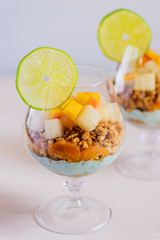 Garnola with yogurt, melon, peach and spirulina in a glass.