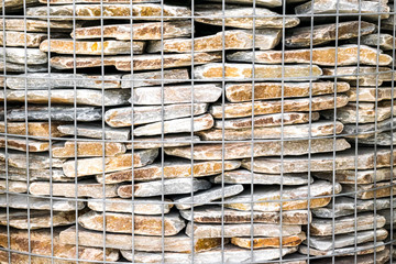 Brown white large flat stones background. Natural environmental decorative material behind a metal mesh.