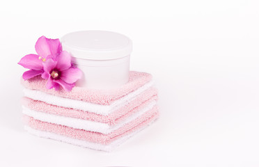 Obraz na płótnie Canvas Soft towels and pink flowers. Mock-up jar spa cosmetics. Spa concept. Soft towels copy space