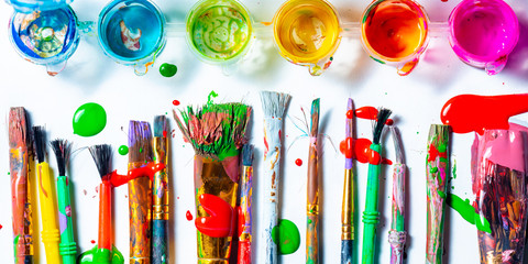 Row Of Messy Colorful Paint Brushes And Containers On Isolated White Background - Creativity Concept - obrazy, fototapety, plakaty