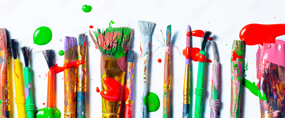 Wall mural row of messy colorful paint brushes on isolated white background - creativity concept