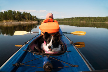 The owner and the dog in a life jacket floating in a kayak boat.