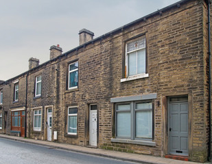a row of traditional english old working class terraced houses on a street with grey cloudy sky