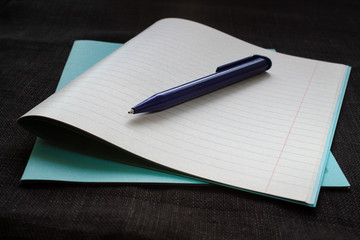 Back to school concept. Notebook with notice paper and pen on black background