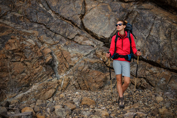 Hiker girl in sunglasses with backpack in mountains