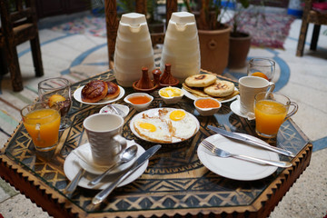 Breakfast in morocco: eggs, fresh orange juice, green tea, coffee, pancakes, butter, honey and chocolate mousse.