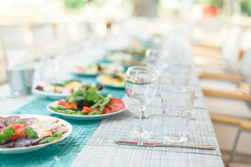 outdoor lunch in the sun. Laid blue table with wine glasses and plates