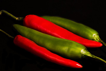 Chili peppers on a dark black background. Spicy chilies on dark surface photographed from front.