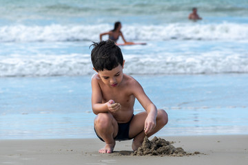 Boy on the beach playing mini sand castle (photo 1).