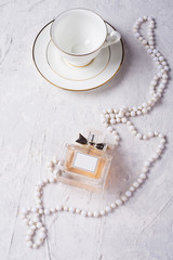 porcelain cup with perfume and neck beads around background