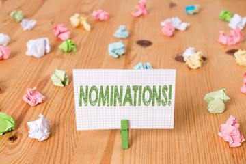 Conceptual hand writing showing Nominations. Concept meaning action of nominating or state being nominated for prize Colored crumpled papers wooden floor background clothespin
