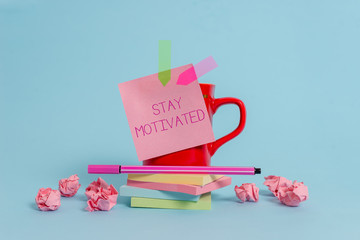Writing note showing Stay Motivated. Business concept for Reward yourself every time you reach a goal with knowledge Coffee cup pen note banners stacked pads paper balls pastel background