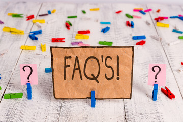 Conceptual hand writing showing Faq S. Concept meaning list of questions and answers relating to particular subject Crumbling sheet with paper clips placed on the wooden table