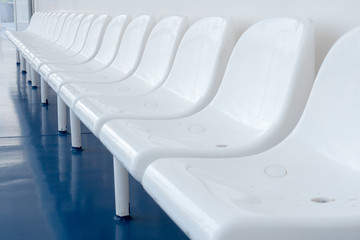 Empty plastic chairs on ferry boat ship liner for passengers. Sea excursion. Happy summer vacations. Row of empty chairs White chairs on blue floor for visitors to rest Vacant seats Bad tourist season