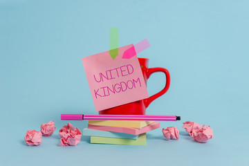 Writing note showing United Kingdom. Business concept for Island country located off the northwestern coast of Europe Coffee cup pen note banners stacked pads paper balls pastel background