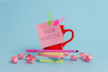 Writing note showing Think Positive. Business concept for The tendency to be positive or optimistic in attitude Coffee cup pen note banners stacked pads paper balls pastel background