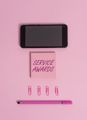 Text sign showing Service Awards. Business photo showcasing Recognizing an employee for his or her longevity or tenure Colored blank sticky note clips smartphone pen trendy pastel background