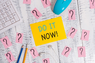 Writing note showing Do It Now. Business concept for not hesitate and start working or doing stuff right away Writing tools and scribbled paper on top of the wooden table