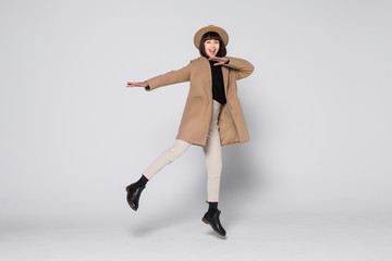 Charming young woman wearing a coat jump isolated over white background.