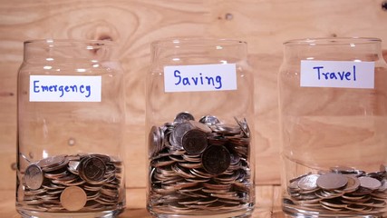 Time lapse save money coin with separate expenses for emergency, saving and travel into the glass on wood background (Thai currency, THB coin)