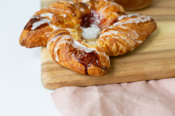 Close up of Strawberry and Sweet Cheese Danish with Icing Drizzle on Wooden Serving Board, Pink Napkin, Fruit Pastry Flat Lay on White Background