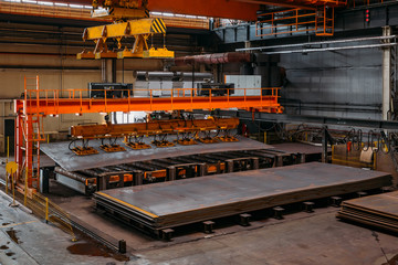 Overhead crane with vacuum handling grippers lifting iron sheets