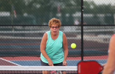 A senior woman plays pickleball